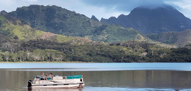 a small boat in a body of water with a mountain in the background